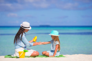 Young mother applying sunscreen on her kid