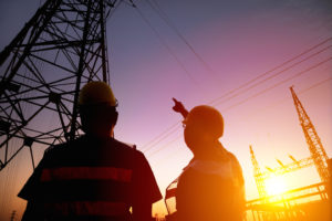 two worker watching the power tower and substation with sunset background